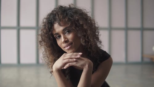 Portrait of a Cute Young Woman with Curly Hair and a Charming Smile