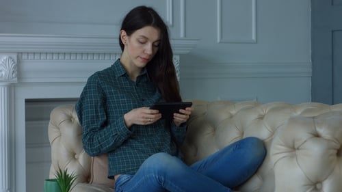 Woman Using Tablet While Sitting on Couch Indoors