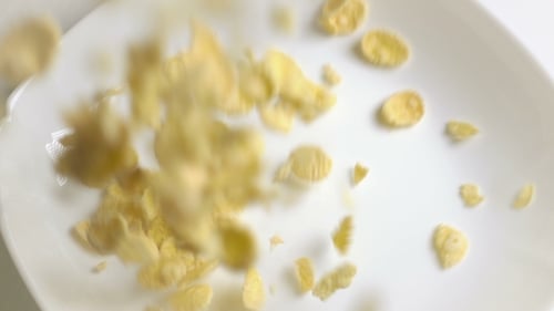 Corn Flakes Cereal Falling into a White Bowl