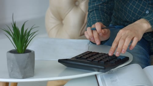 Person Calculating Finances With Calculator and Pen