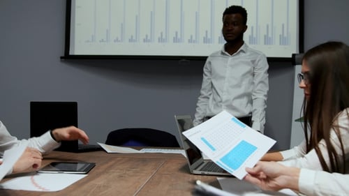 African American Coach Gives Corporate Presentation for Businesspeople in Office