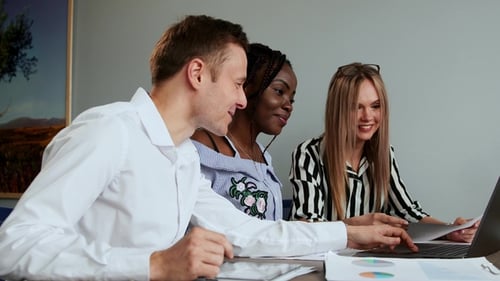 Smiling Team Working Together Using a Laptop