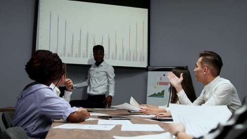 African American Coach Gives Corporate Presentation for Businesspeople in Office