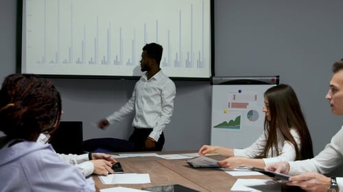 African American Coach Gives Corporate Presentation for Businesspeople in Office