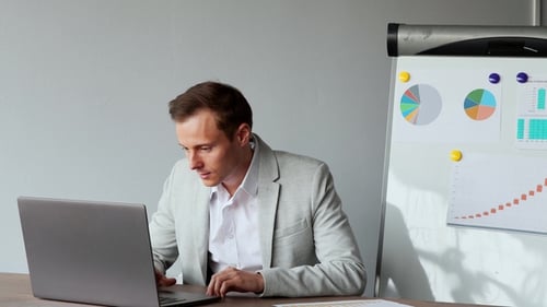 European Male Sitting at a Laptop in the Office with a White Shirt