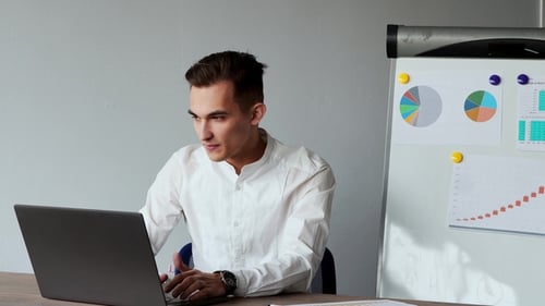European Male Sitting at a Laptop in the Office with a White Shirt
