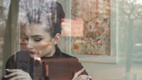 Young Woman Looking Outside Through the Window in a Coffee Shop
