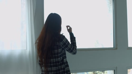 Woman Stands at Window in Apartment