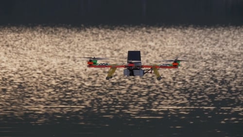 Drone Flies Above Glimmering Water at Sunset