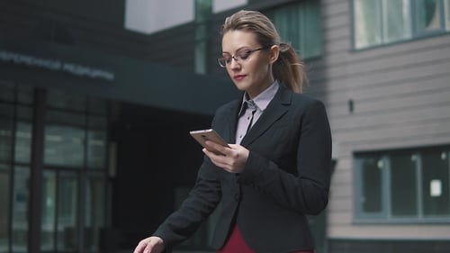 Busy Business Woman Walking Down the Street and Reading a Message From a Smartphone