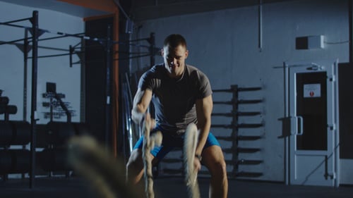 Man Does Battle Rope Workout at the Gym