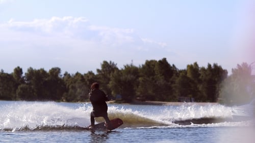 Man Wakeboarding on Waves. Water Skiing on Lake Behind Boat. Wakeboarder Surfing