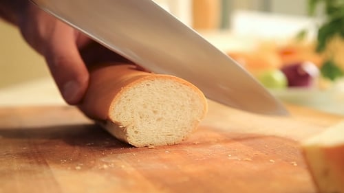 Man Slicing Baguette on Wooden Cutting Board