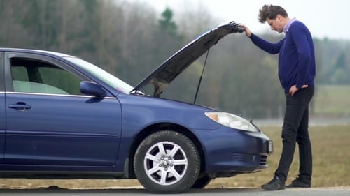 Man Looking Under Hood of Broken Down Car