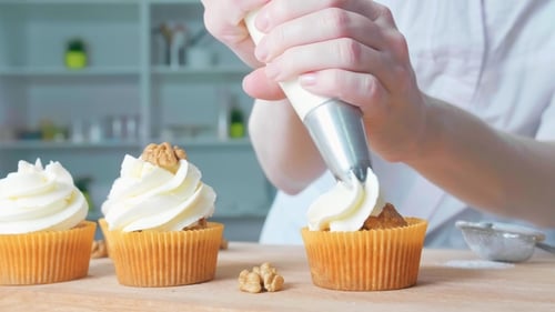 Woman Icing Cupcakes with Delicious Cream Frosting