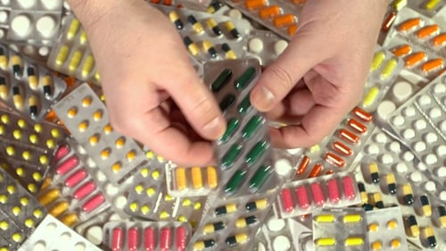 Hands Holding Medicine Blister Pack Over Table