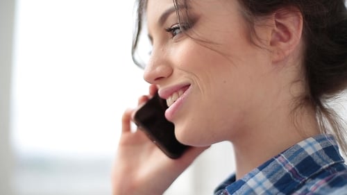 A young woman is talking on the phone with her boyfriend and smiling. Close-up portrait.