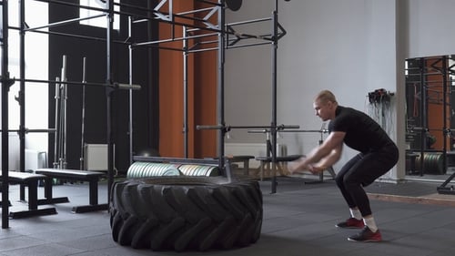 Fitness-Mann macht Vorschlaghammer-Swing-Übung im Fitnessstudio