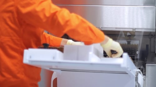 Pharmazeutischer Arbeiter beim Laden medizinischer Fläschchen an einer pharmazeutischen Verpackungsmaschine