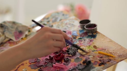 El artista mezcla pintura en paleta con un pincel