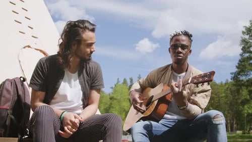 Friends Playing Guitar Together Outdoors on Sunny Day