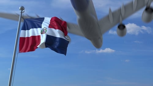 Commercial Airplane Flying Above Waving Flag of the Dominican Republic