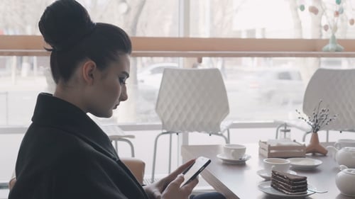Woman Using App on Smartphone in Cafe Drinking Coffee Smiling and Texting on Mobile Phone