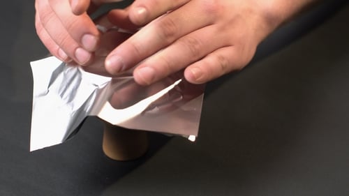 Adult Hands Preparing Small Silver Bowl With Foil