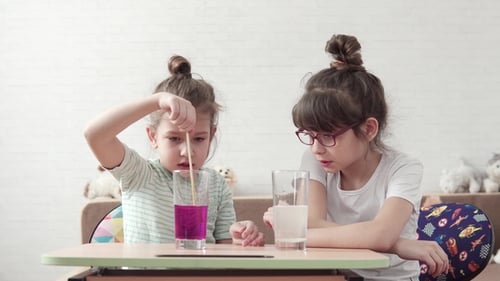 Young Girls Performing Science Experiment at Table
