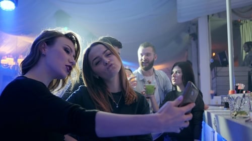 Fashionable Girls at Nightclub Makes Selfie Photo on Mobile Phone on Background of Disco Lights