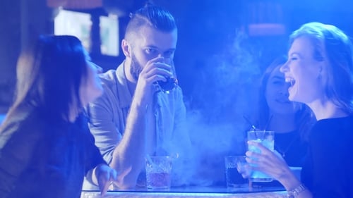 Young Adults Socializing at Colorful Nightclub With Drinks