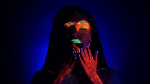 Girl Sexy Smears and Rubs Fluorescent Paint on Her Body. Dye Glowing Under UV Black Light. Woman