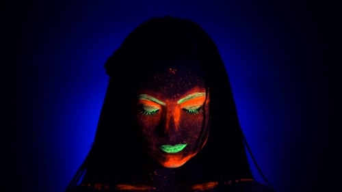 Fashion Model Woman with Braids in Neon Light. Fluorescent Makeup Glowing Under UV Black Light