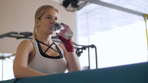 Athletic Woman Drinking Water in Gym