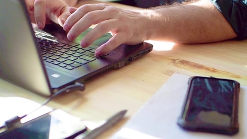 Hands Typing on Laptop Keyboard at Desk
