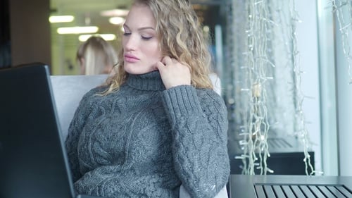 Woman Working on Laptop in Bright Cafe