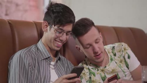 Portrait of Two Male Friends Resting in the Restaurant Sitting on the Leather Sofa Talking