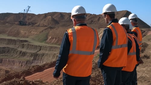 Panorama Shot of a Group of Workers in Overalls Actively Speaking on Board a Bauxite Quarry.