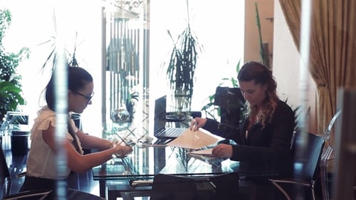 Dos mujeres de negocios discuten un proyecto empresarial sentadas en una mesa en la oficina una frente a la otra
