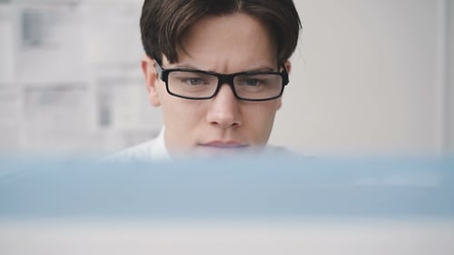 Worried Businesman Working Diligently with Computer in Office