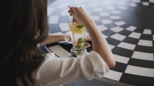 View of Girl Stirring the Lemonade with Tubule