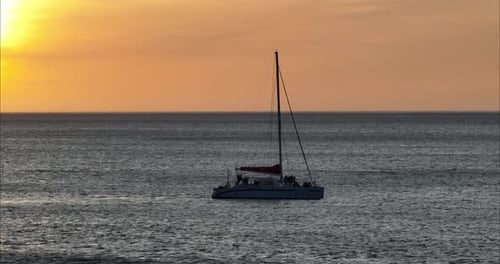 Sailboat Glides across Ocean at Sunset