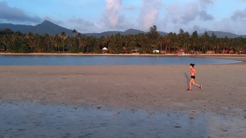 Young Woman Jogging at the Beach on Sunset