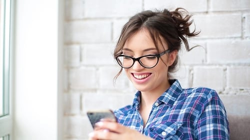 Joyful Young Woman Talking on Mobile Phone at Home