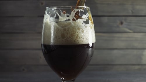 Dark Beer Poured into Glass with Foamy Head