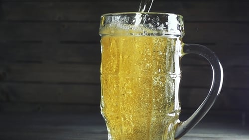 Golden Beer Pouring Into Glass Mug Close Up