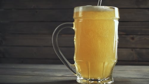 Photo de verser de la bière dans une chope à bière. Sur fond en bois