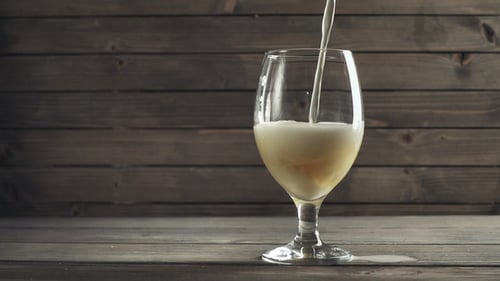 Beer Pouring into Glass on Wooden Background