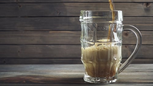 Foamy Drink Being Poured in Glass Mug