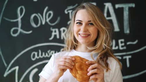 Woman Eating a Pastry and Smiling Cheerfully